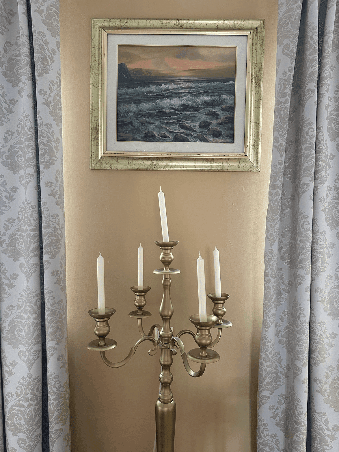 Elegante Dekoration mit einem hohen Kerzenleuchter und einem gerahmten Gemälde an der Wand.