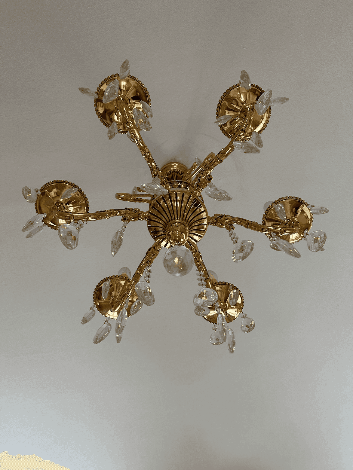 Detailaufnahme eines opulenten goldenen Kronleuchters mit Kristallverzierungen an der Decke.