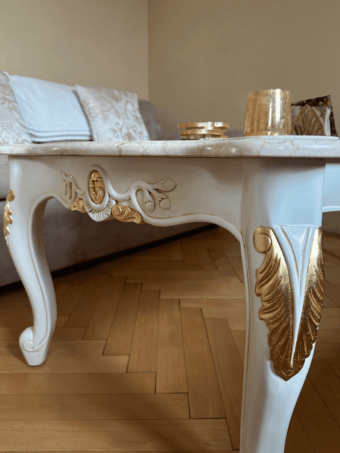Detailaufnahme eines eleganten Couchtisches mit goldenen Verzierungen und einer Marmorplatte.