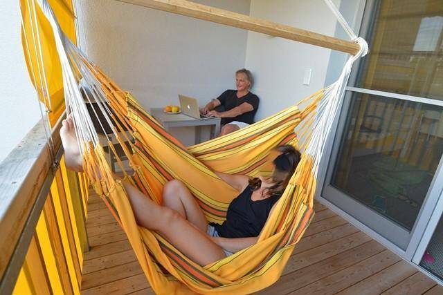 Gemütlicher Balkon mit Hängematte und Holzboden, ideal zum Entspannen und Arbeiten im Freien.