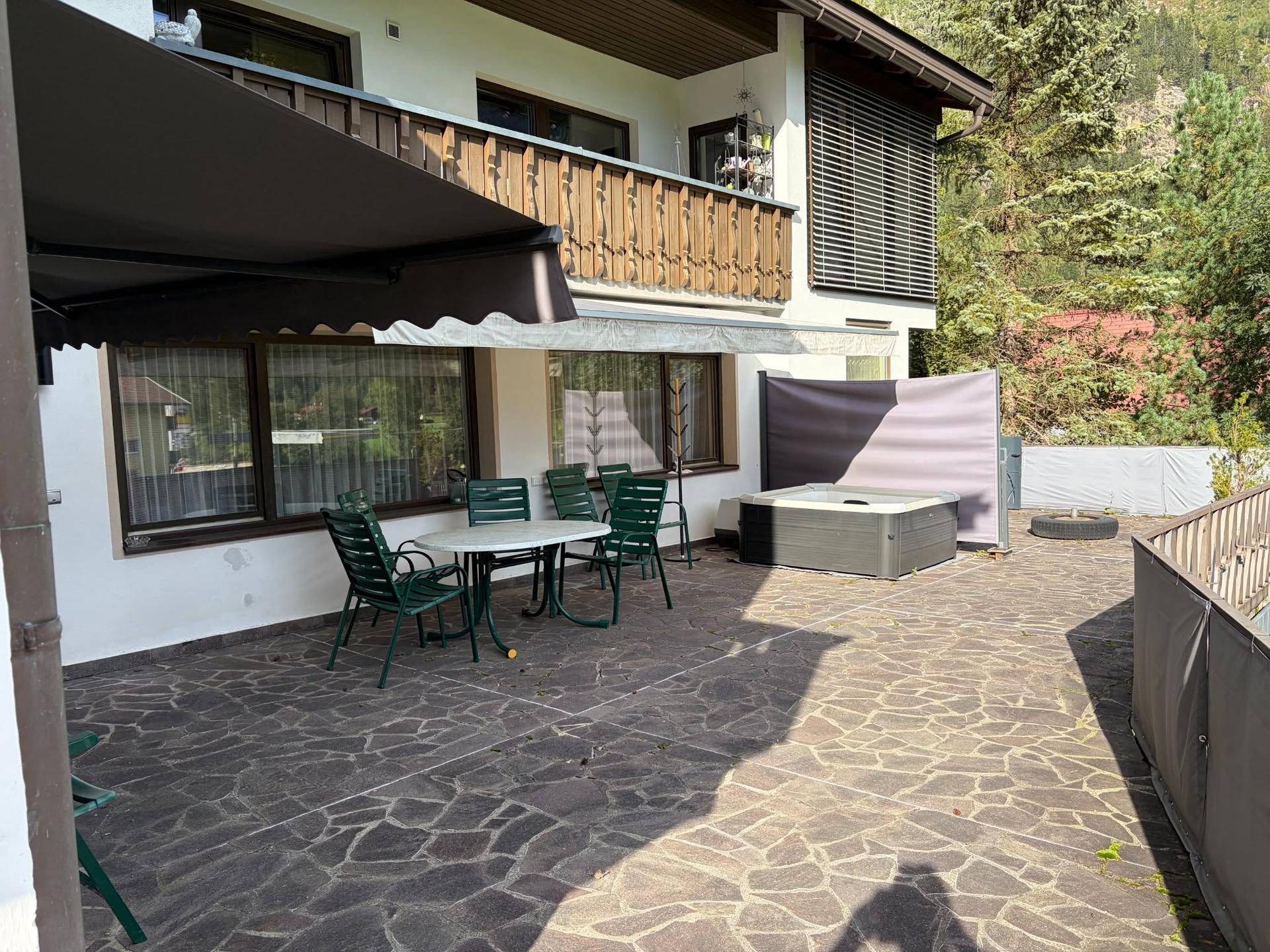 Geräumige Terrasse mit Markise, Gartenmöbeln und einem entspannenden Whirlpool.