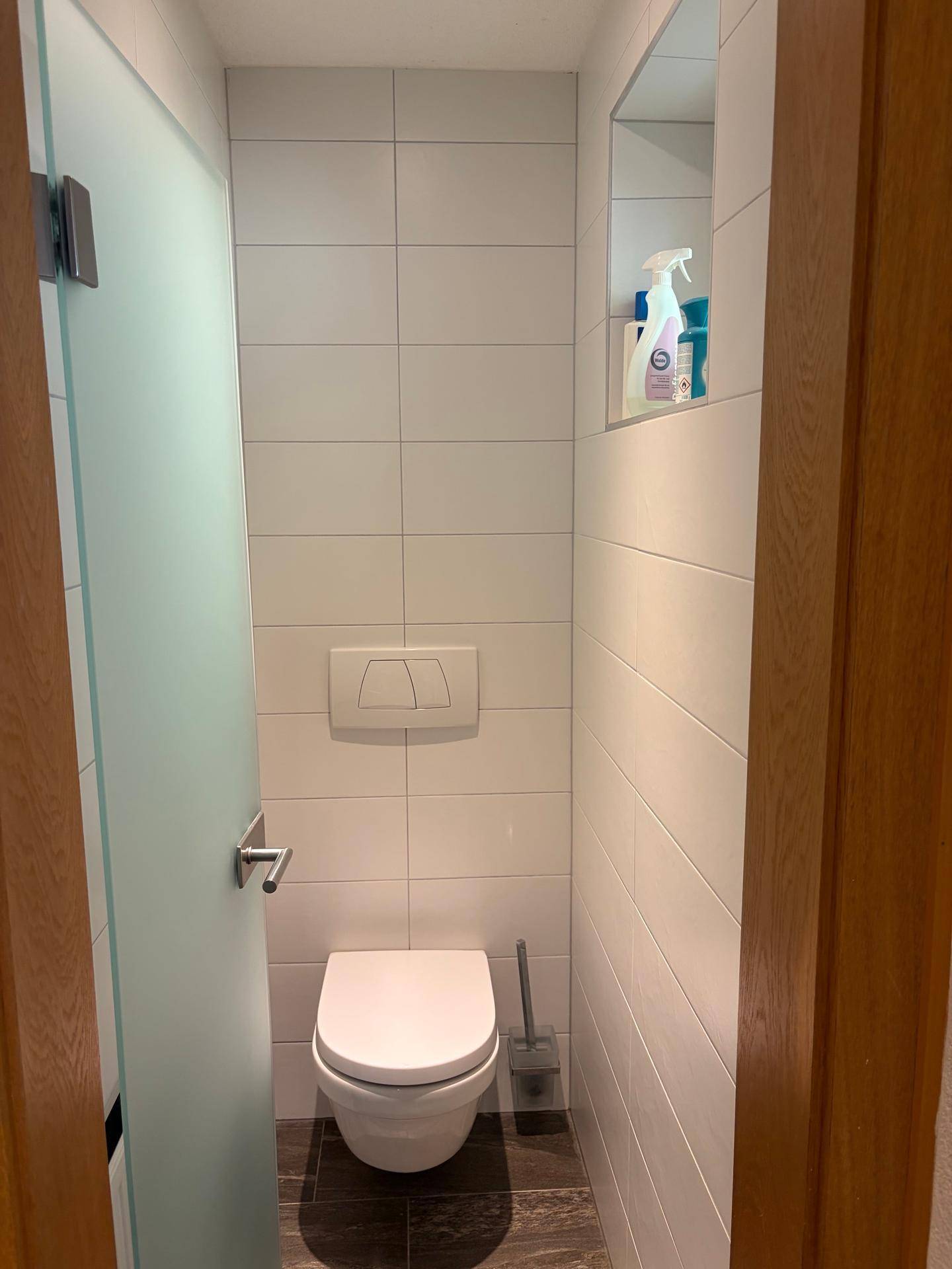 Separates Gäste-WC mit wandhängender Toilette und weißen Fliesen.