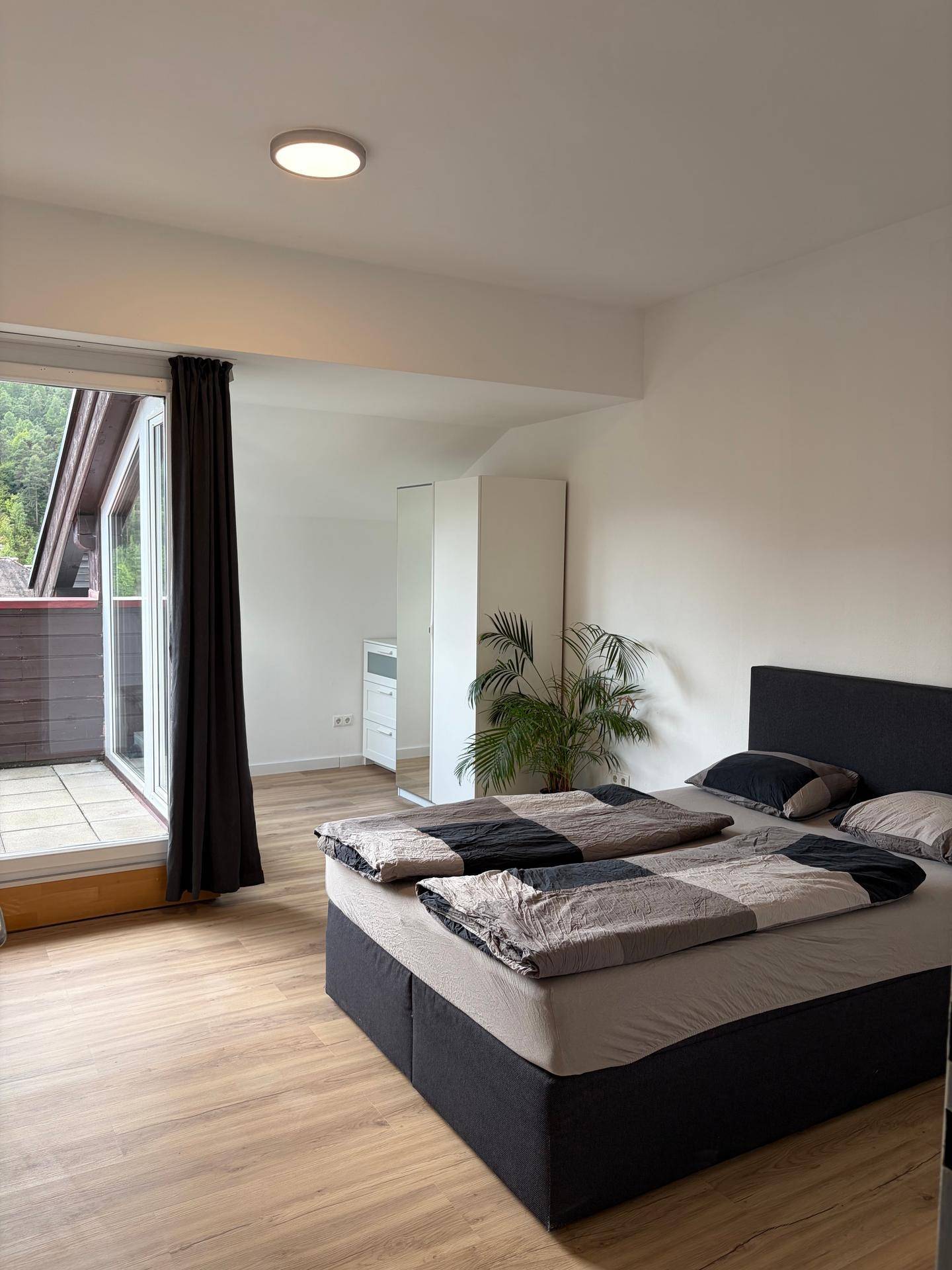 Gemütliches Schlafzimmer mit Doppelbett, Pflanzen und direktem Zugang zum Balkon.