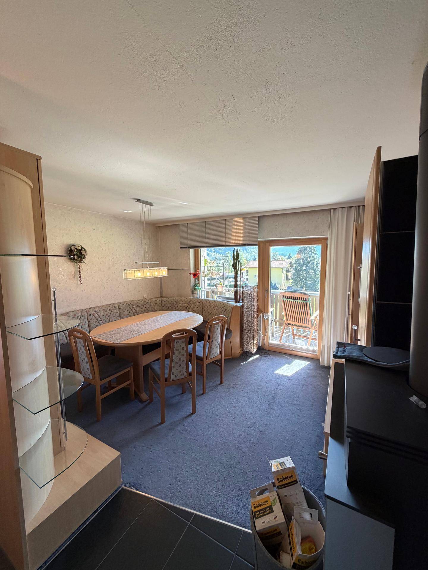 Gemütlicher Essbereich mit runder Eckbank, Teppichboden und Zugang zum Balkon.