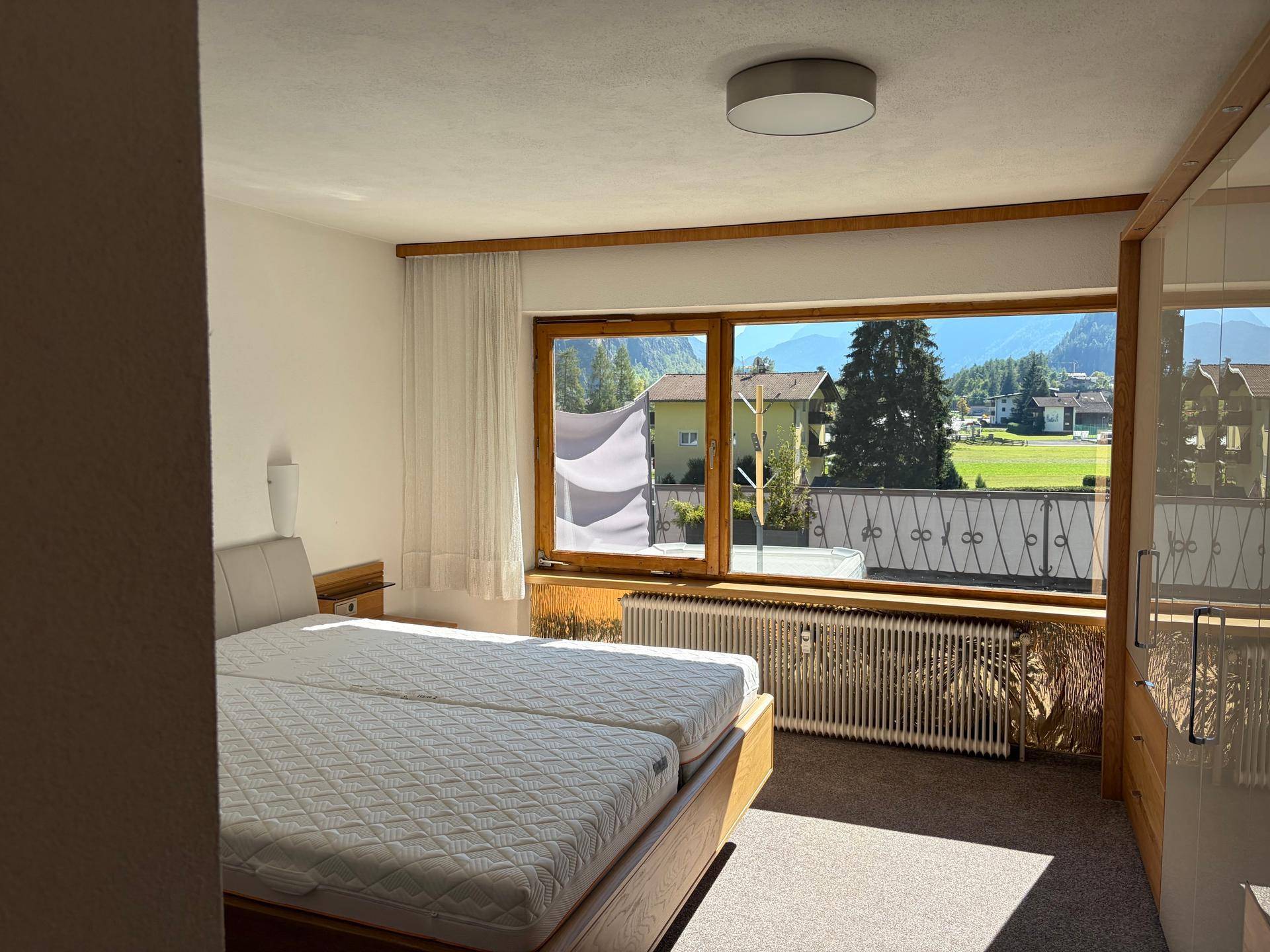 Gemütliches Schlafzimmer mit Doppelbett, Holzmöbeln und weitem Blick ins Grüne.