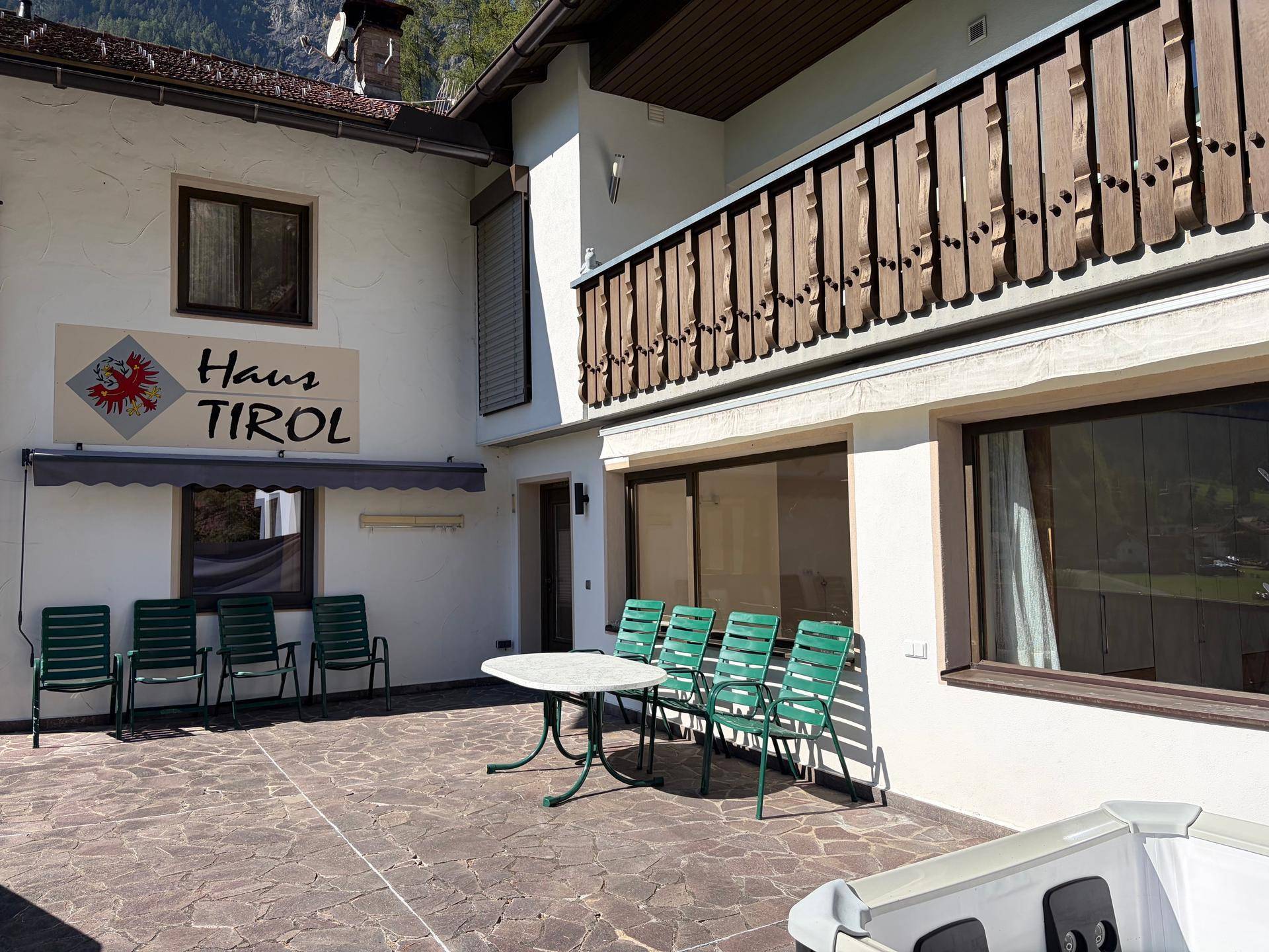 Große gepflasterte Terrasse mit Sitzgelegenheiten und einem Whirlpool vor dem Haus Tirol.