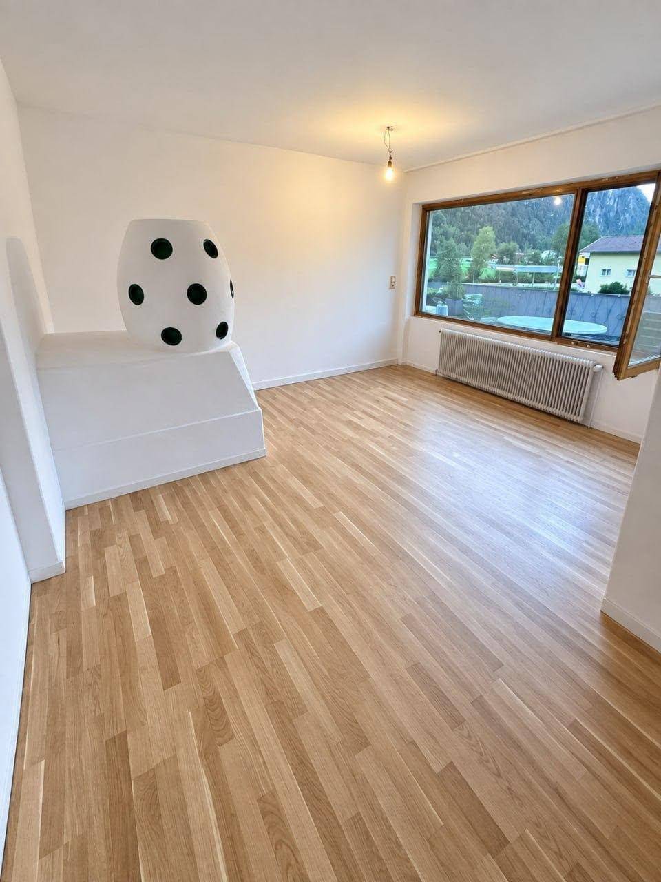 Heller Raum mit Holzboden, großen Fenstern und viel natürlichem Licht.