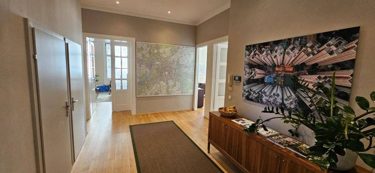 Heller Flur mit Holzboden, einem langen Teppichläufer und moderner Kunst an der Wand.