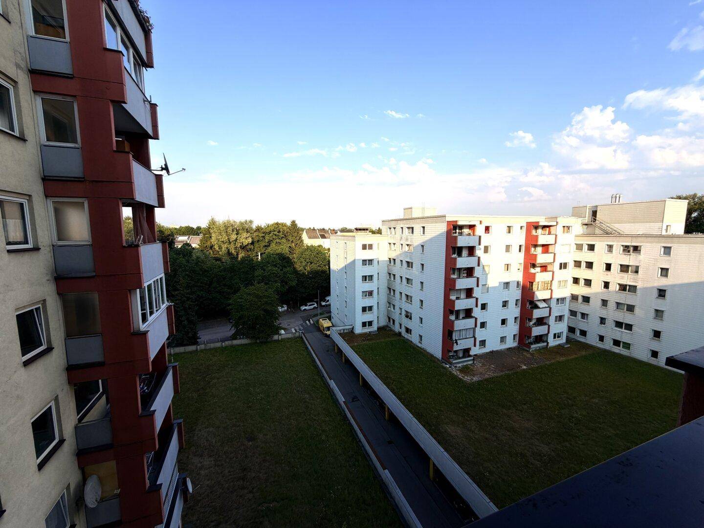 Weitblick vom Balkon über eine Wohnsiedlung mit Grünflächen und klarem Himmel.