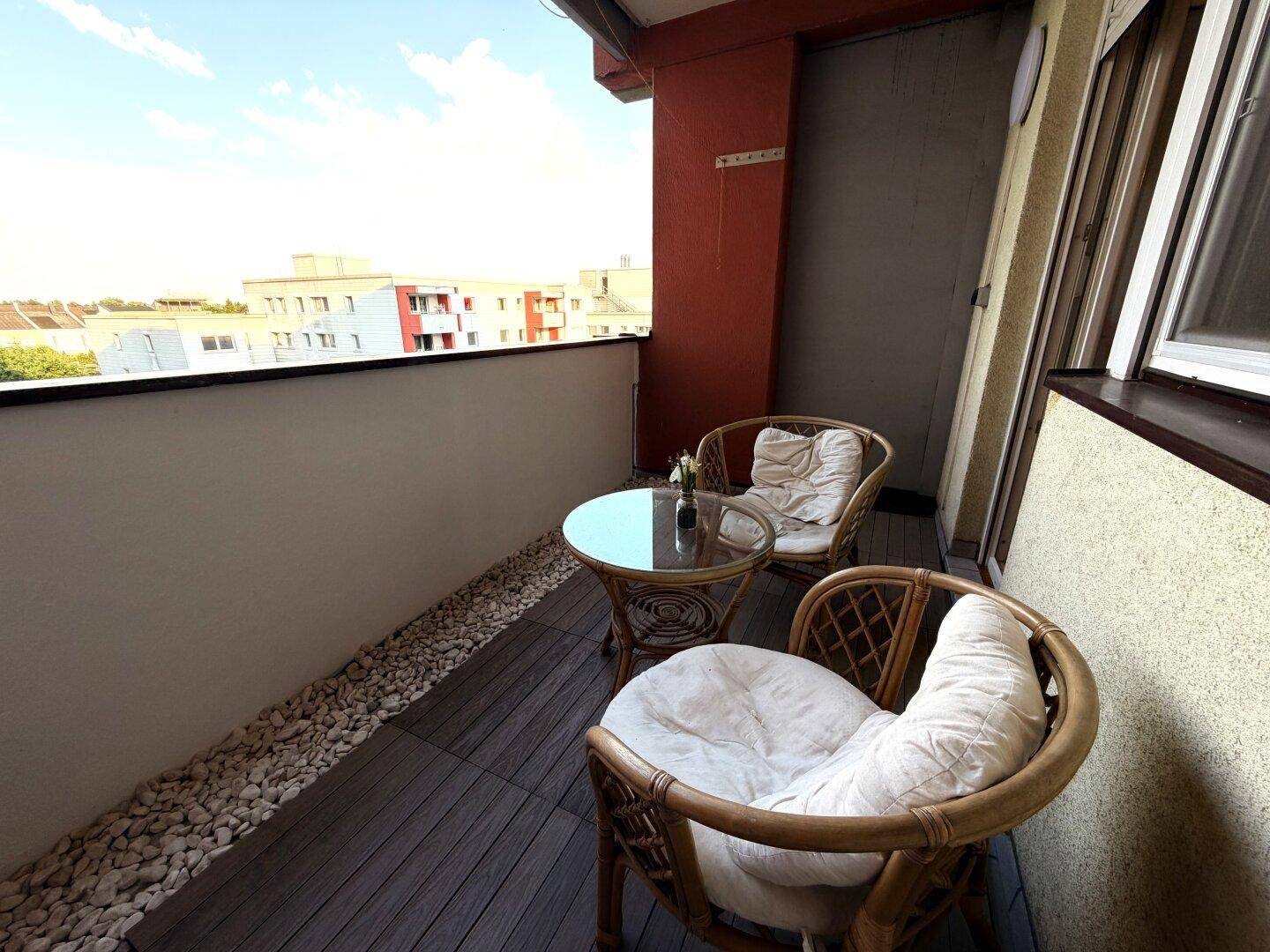 Gemütlicher Balkon mit Rattanmöbeln und Blick auf die umliegenden Gebäude.