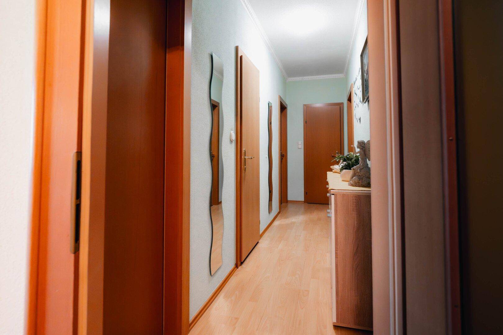 Heller Flur mit Holzboden und mehreren Türen, der die verschiedenen Räume der Wohnung verbindet.