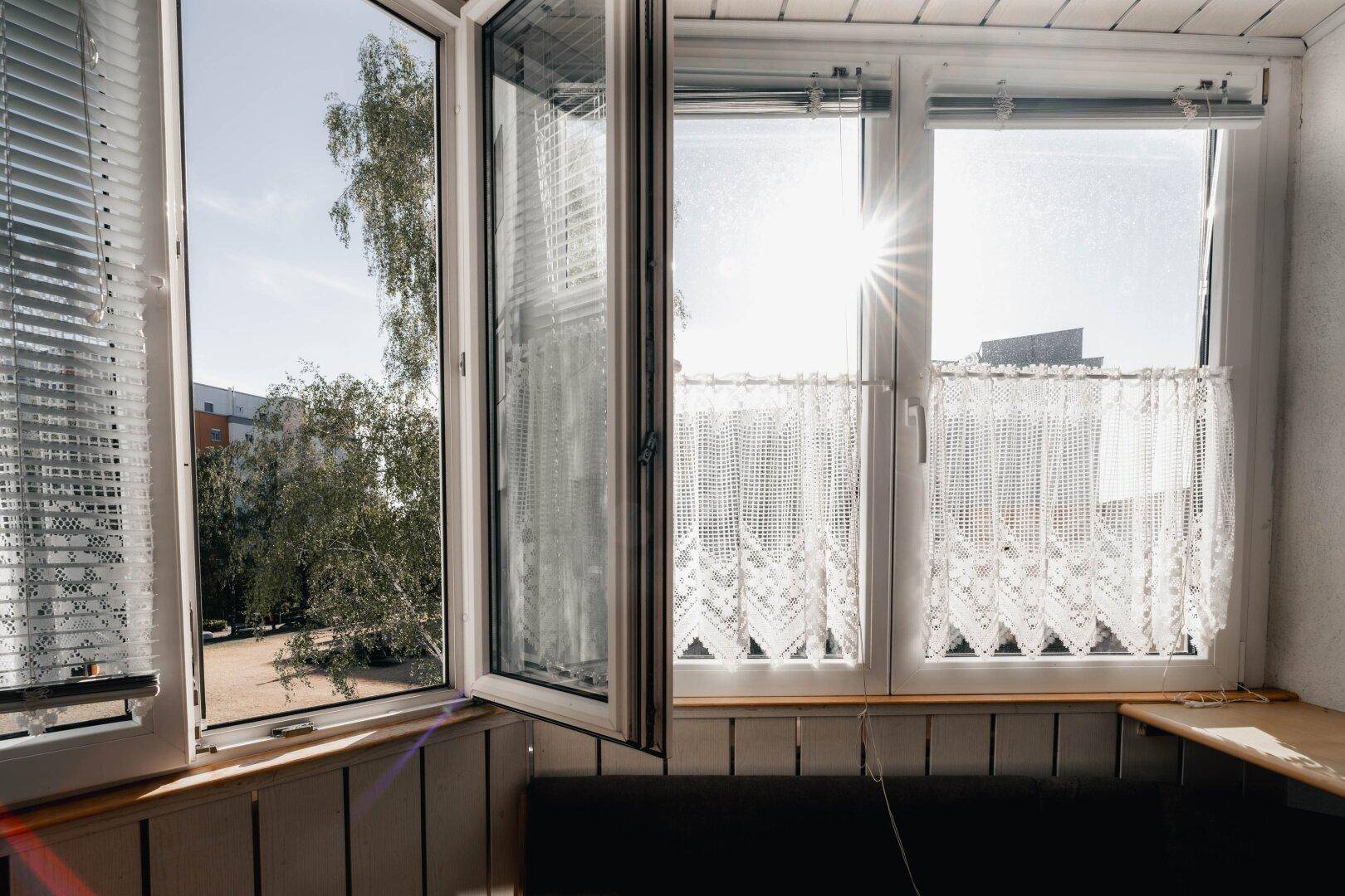 Große Fenster in einem verglasten Balkon lassen viel Sonnenlicht herein und bieten einen schönen Ausblick.