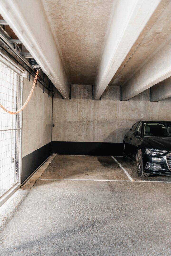 Einzelner Stellplatz in einer Tiefgarage mit Betonwänden und einem geparkten Auto, sicher und geschützt.