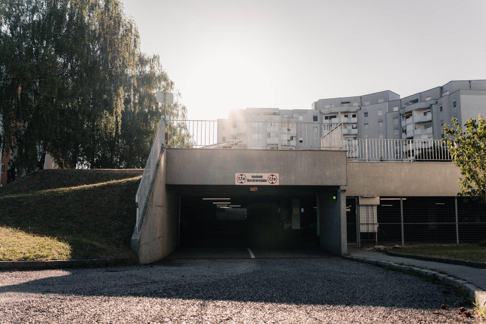 Einfahrt zu einer Tiefgarage mit umliegenden Wohngebäuden und Grünflächen, gut zugänglich.