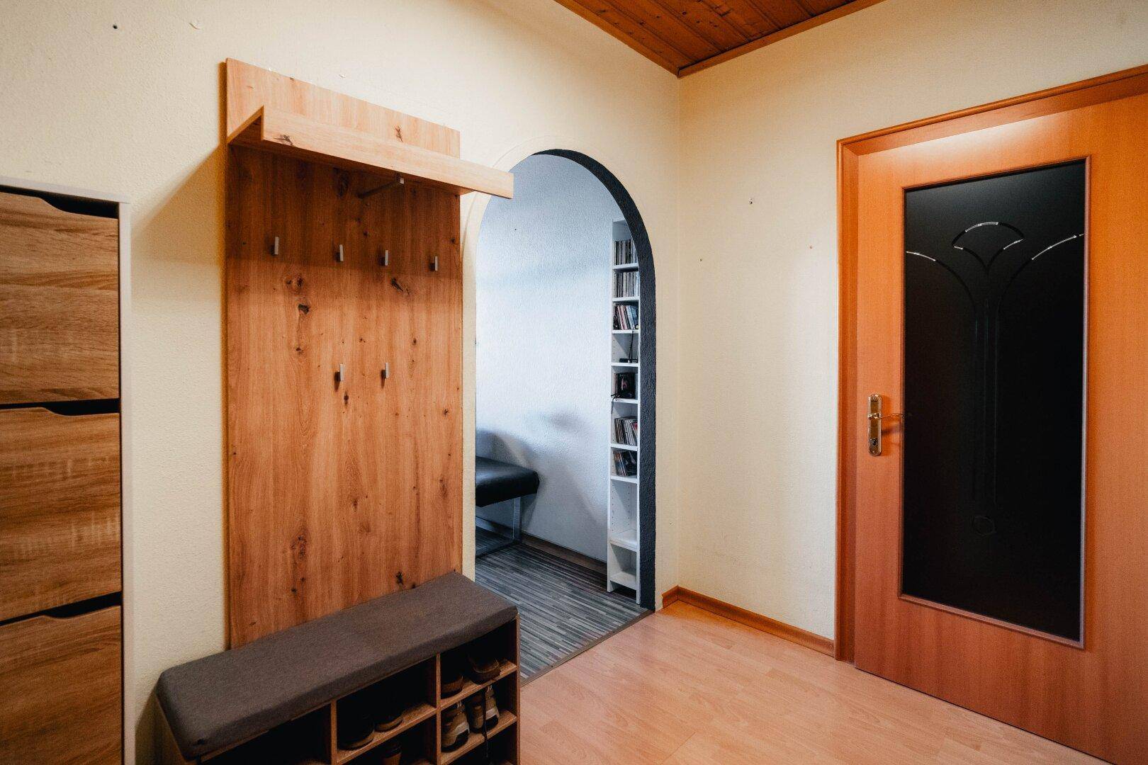 Einladender Eingangsbereich mit Garderobe, Schuhbank und Holzboden, praktisch und hell gestaltet.