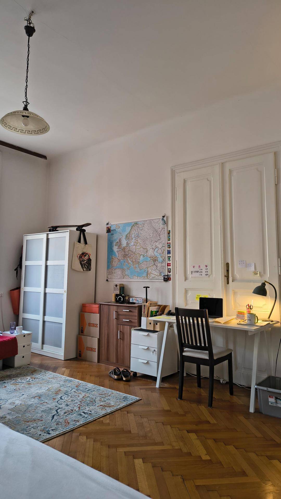 Schlafzimmer mit Fischgrätparkett, Kleiderschrank und einem praktischen Arbeitsbereich am Fenster.
