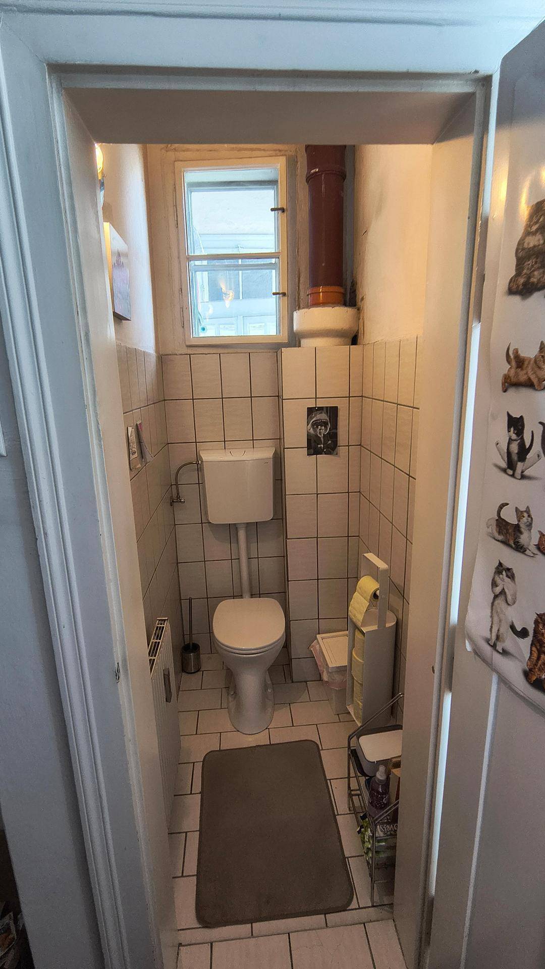 Kleines WC mit Fenster, weißen Fliesen und einem Heizkörper, ideal als Gästetoilette.