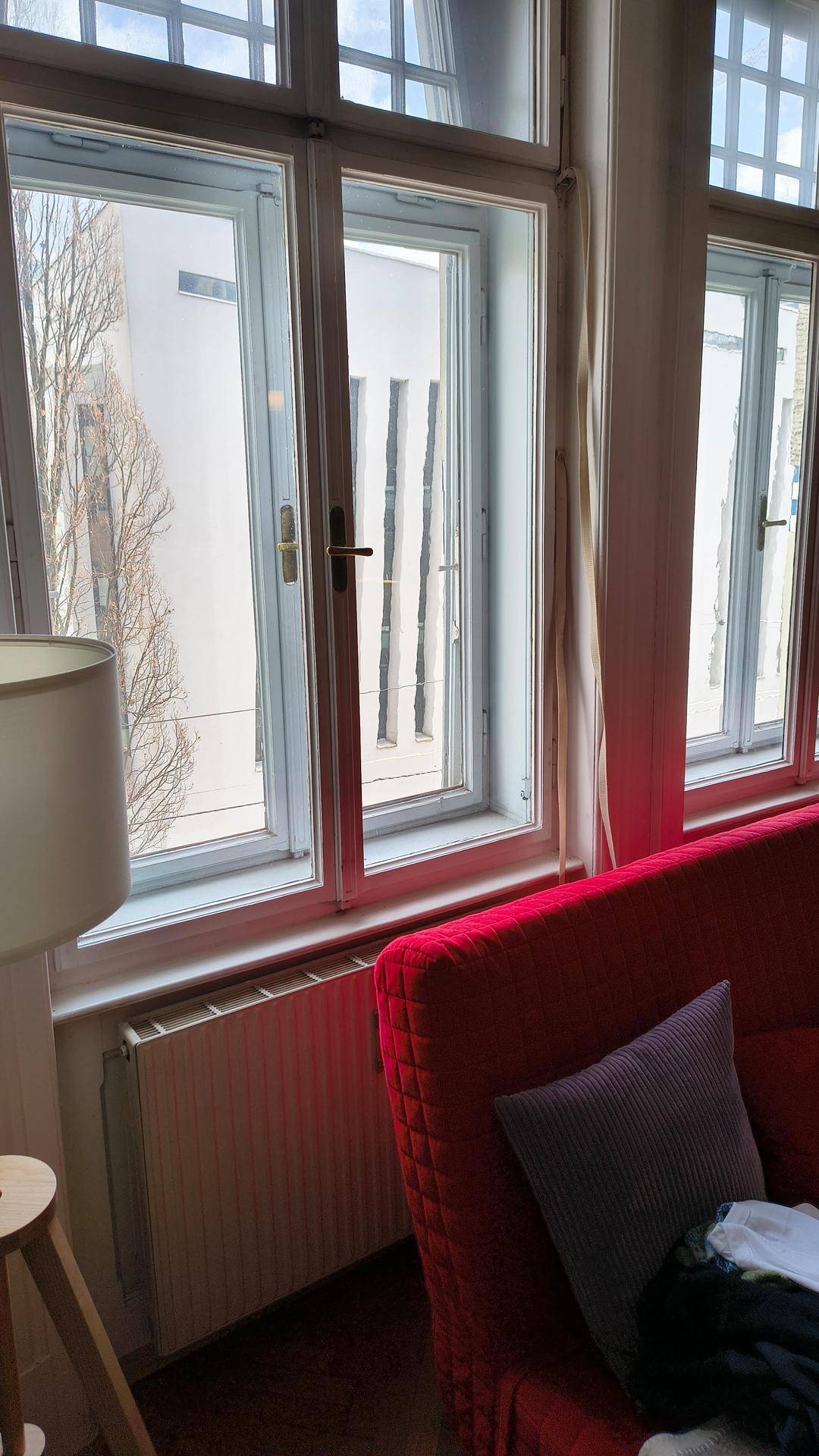 Detailansicht der großen Fenster mit Sprossen und einem Heizkörper im hellen Wohnzimmer.