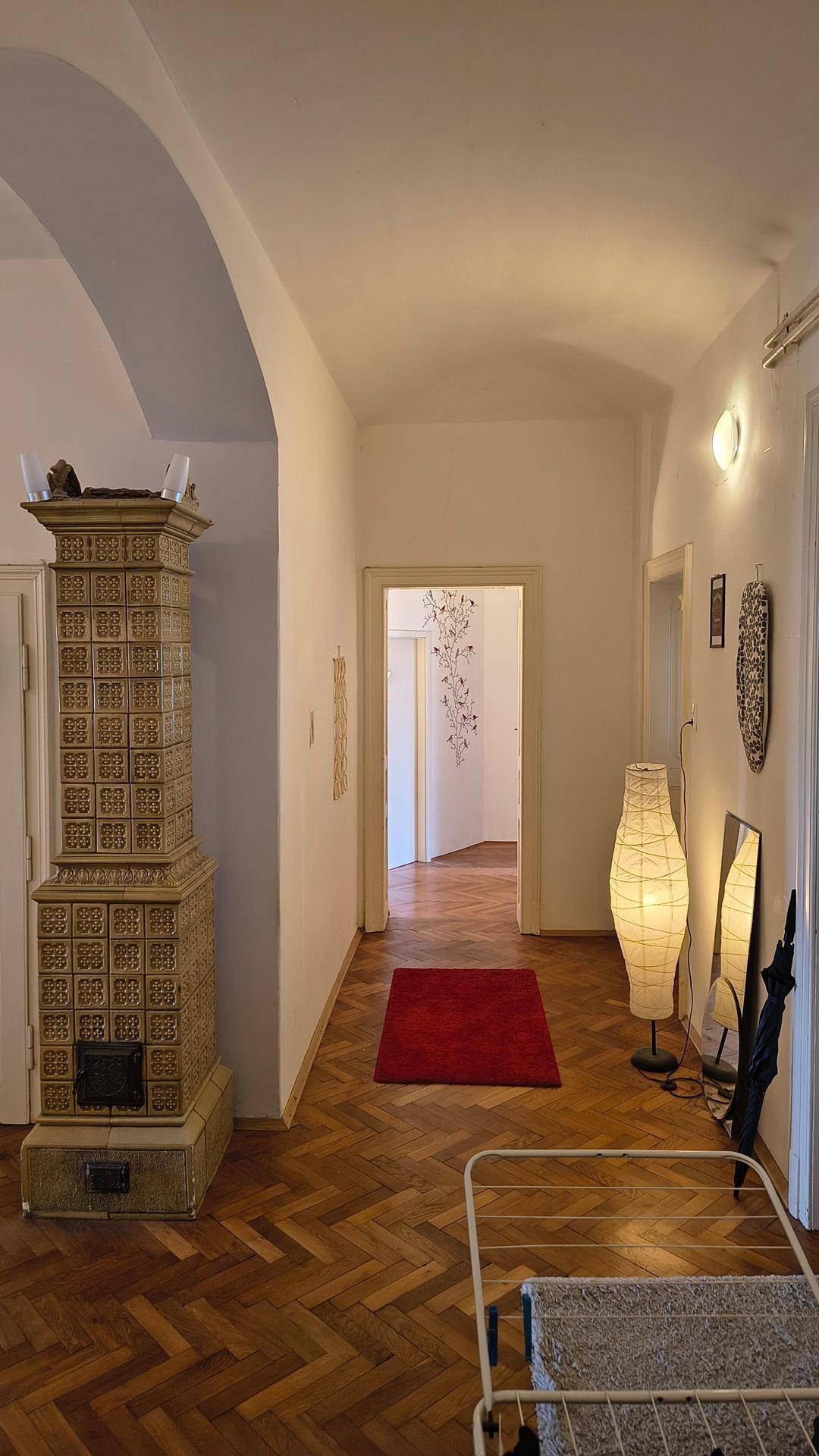 Langer Flur mit Fischgrätparkett, einem Kachelofen und einer eleganten gewölbten Decke.