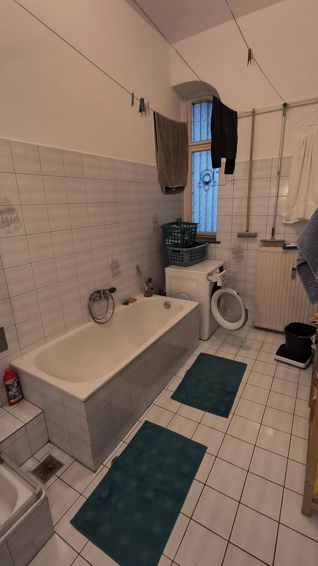 Badezimmer mit Badewanne, Waschmaschine und weißen Fliesen, im Stil der 80er Jahre.