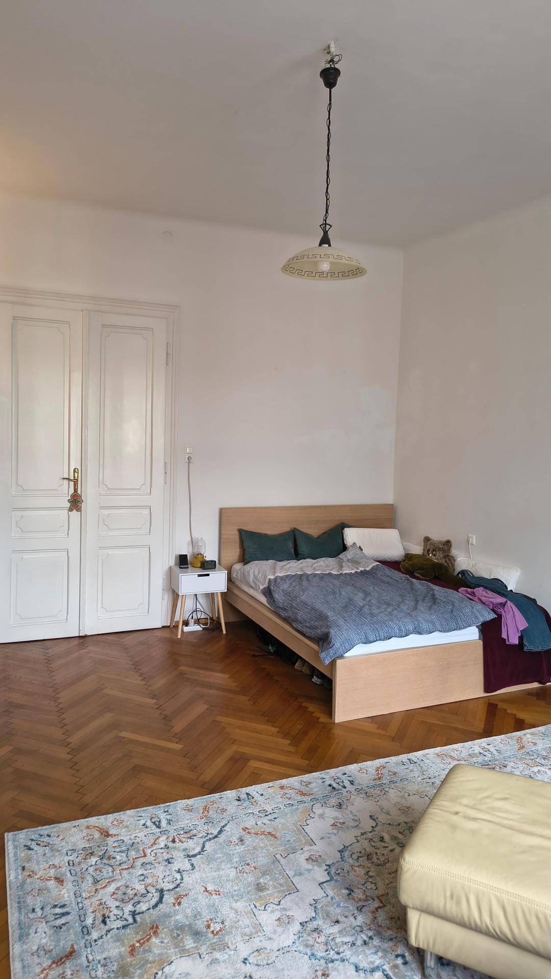 Schlafzimmer mit Fischgrätparkett, Doppelbett und einem Teppich, bietet eine gemütliche Atmosphäre.