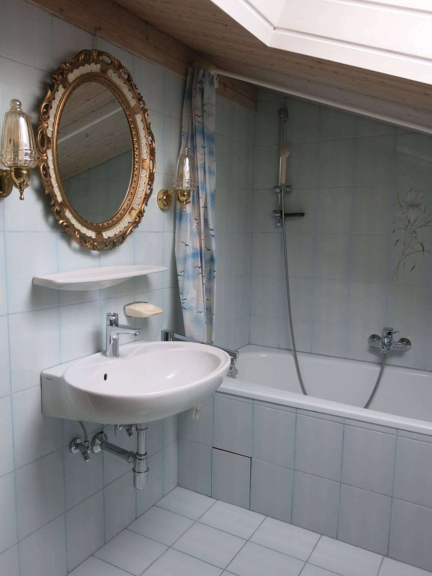 Badezimmer im Dachgeschoss mit Badewanne, Waschbecken und Dachfenster.