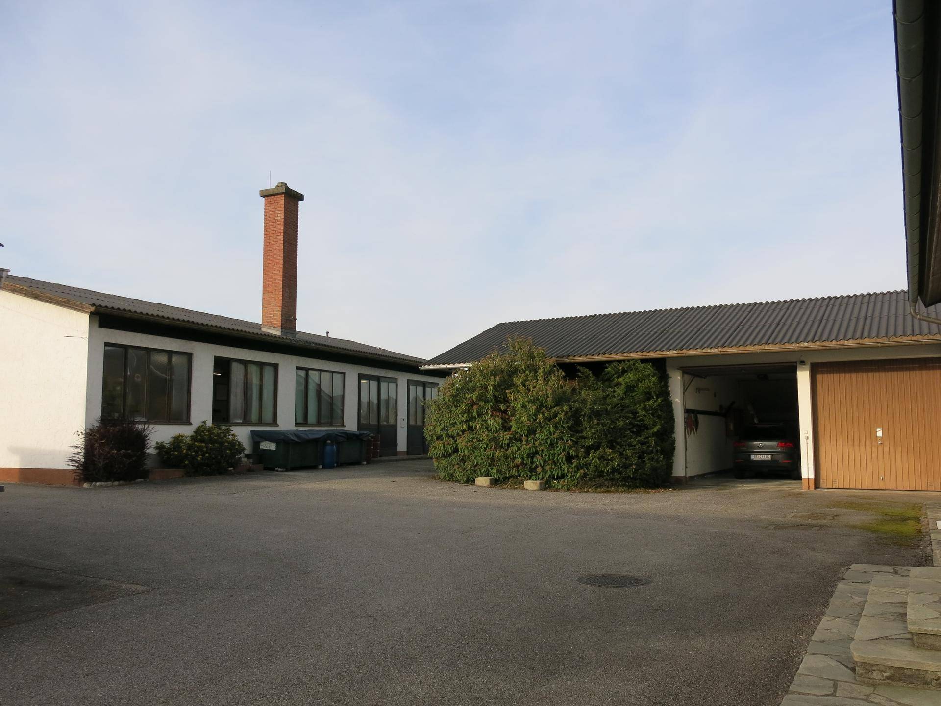 Rückansicht des Gebäudekomplexes mit Werkstätten und Garagen, umgeben von viel Platz.