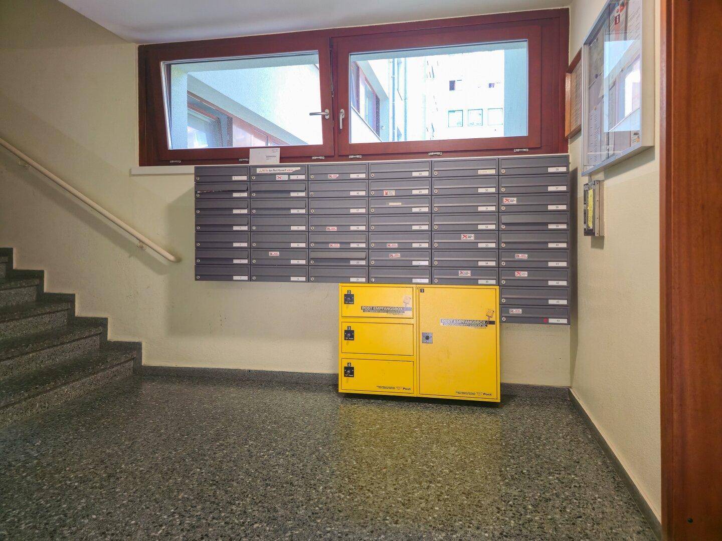 Eingangsbereich des Gebäudes mit Briefkästen, Treppenhaus und Paketbox.