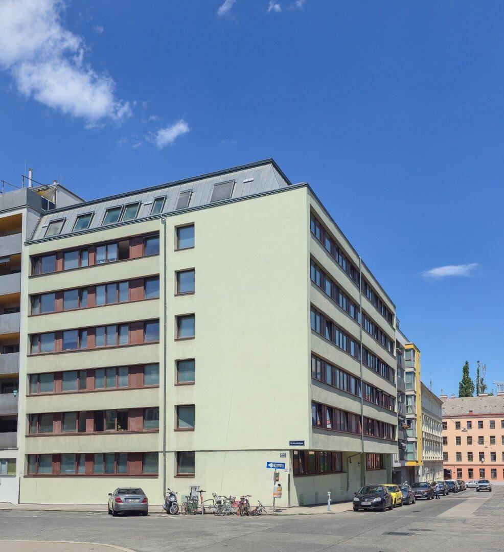 Modernes Mehrfamilienhaus mit mehreren Etagen und klarem Himmel an einem sonnigen Tag.