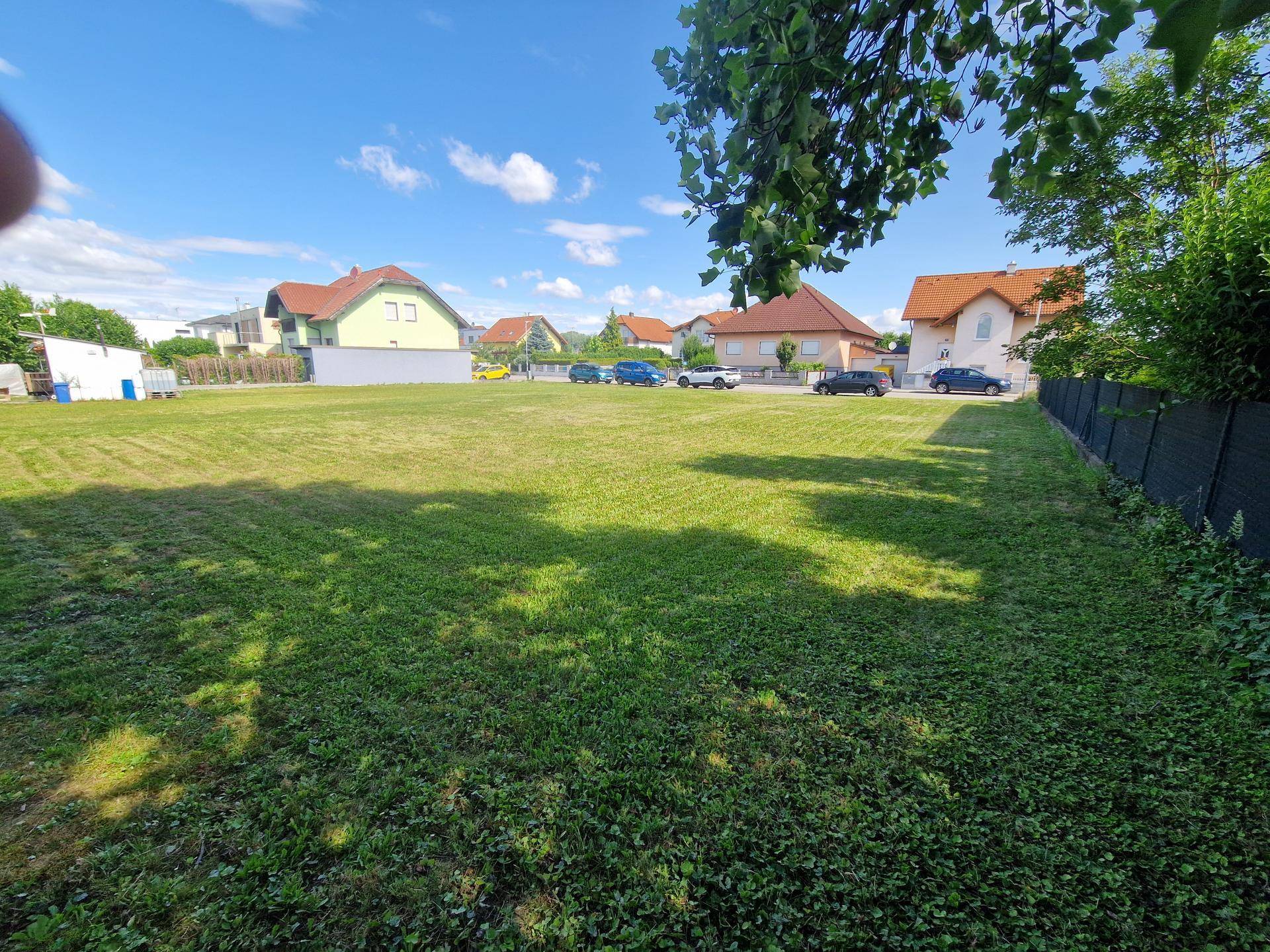 Weitläufiges, sonniges Grundstück mit Rasenfläche und Blick auf die Nachbarschaft und geparkte Autos.