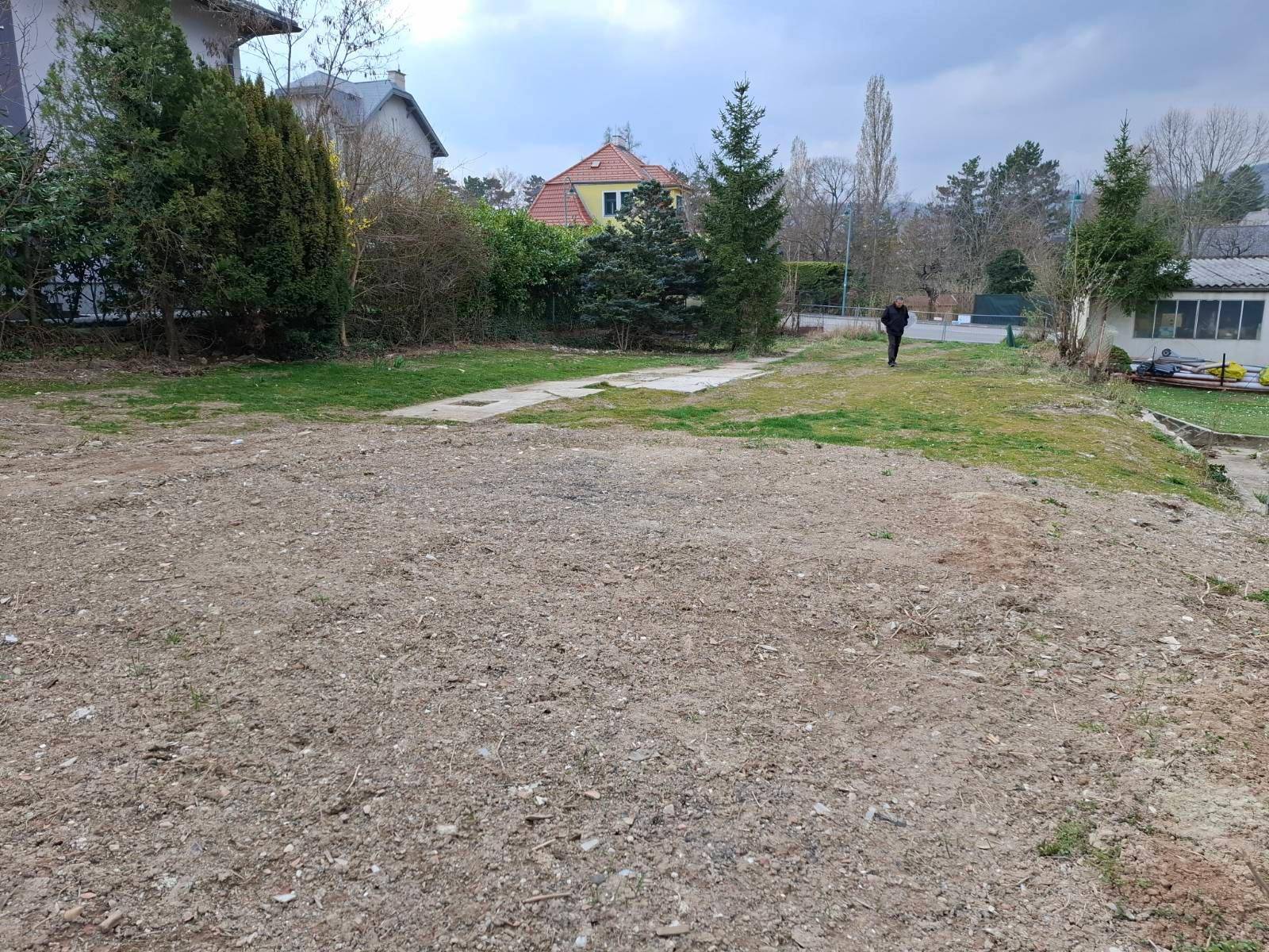 Großes, unbebautes Grundstück mit Erdboden und vereinzelten Gräsern, umgeben von Natur.