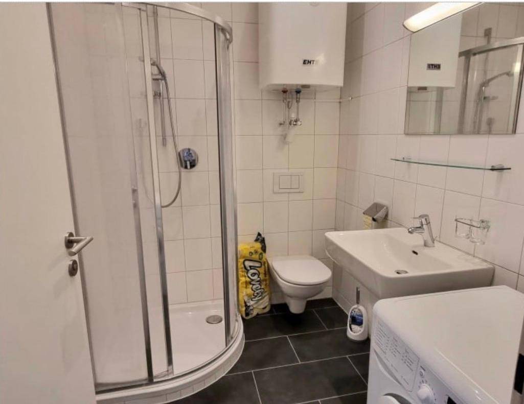 Modernes Badezimmer mit Duschkabine, WC, Waschbecken und Waschmaschine.