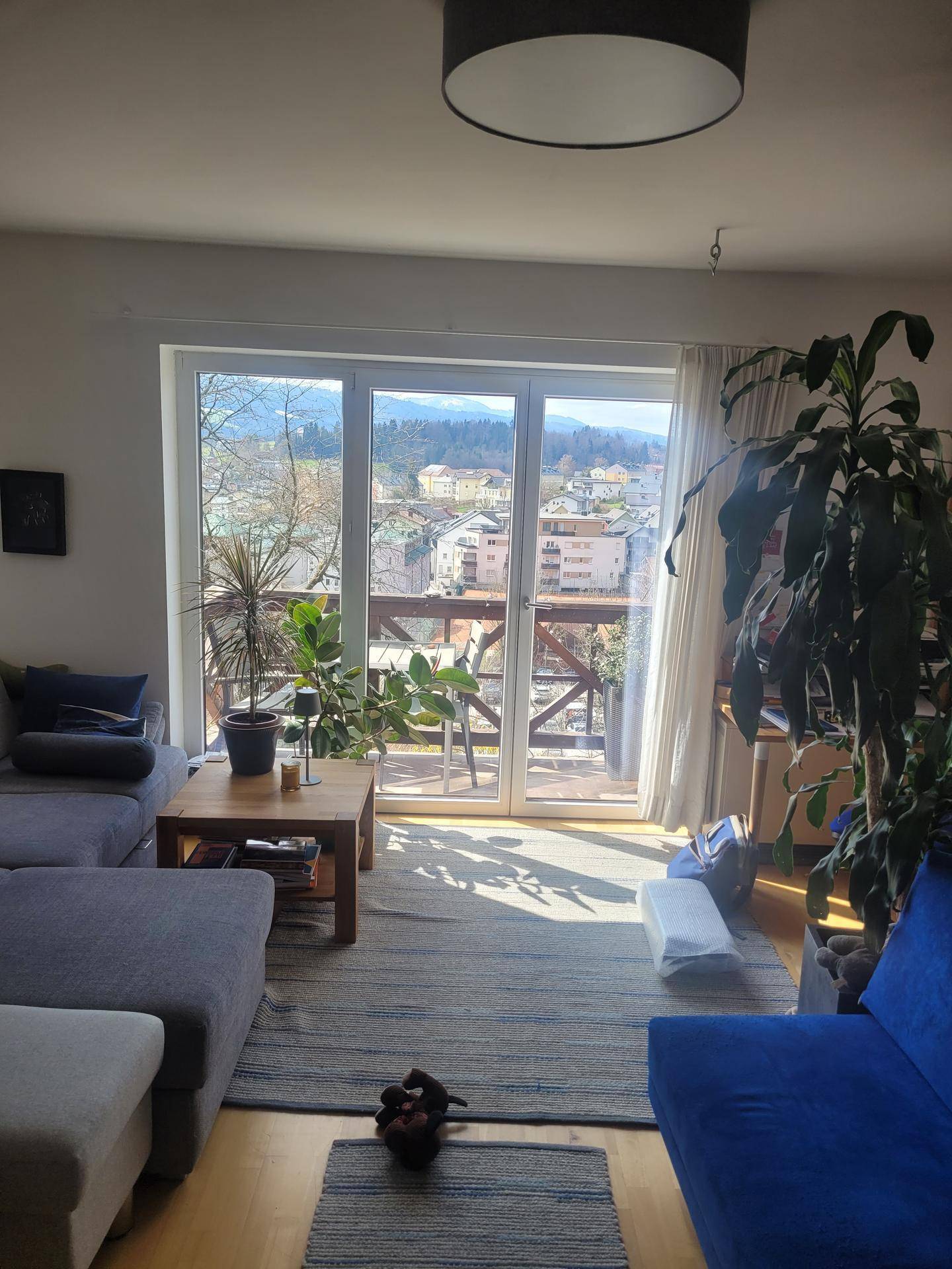 Helles Wohnzimmer mit großzügiger Fensterfront, die viel Tageslicht hereinlässt und einen Ausblick bietet.
