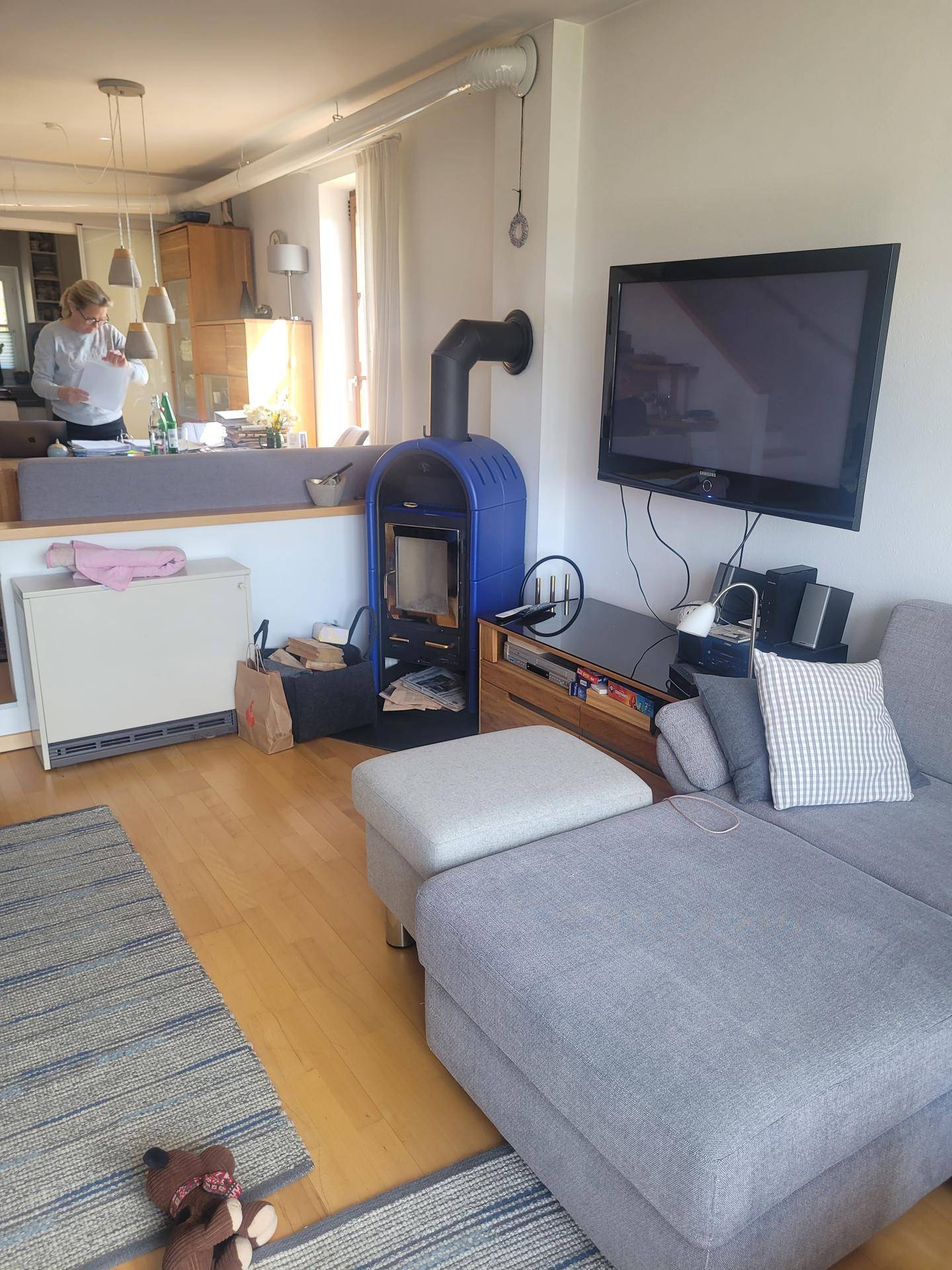 Gemütliches Wohnzimmer mit modernem Holzofen, bequemer Couch und offener Verbindung zur Küche.