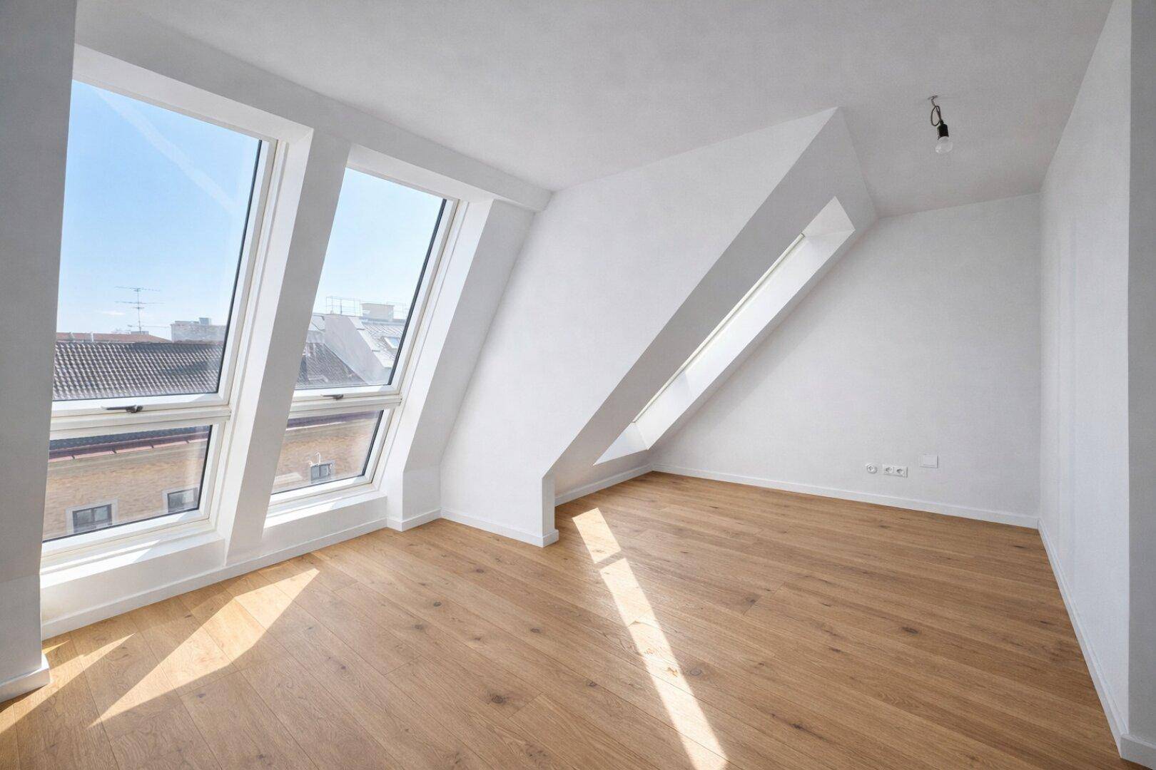 Helles Schlafzimmer im Dachgeschoss mit großen Dachfenstern und neuem Parkettboden.