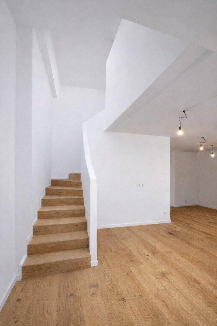 Moderner Treppenaufgang mit Holzstufen und offenem Übergang zu den Wohnbereichen.