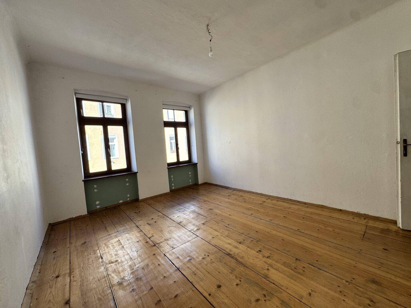 Helles Zimmer mit breiten Holzdielen und hohen Decken, ideal für individuelle Gestaltung.