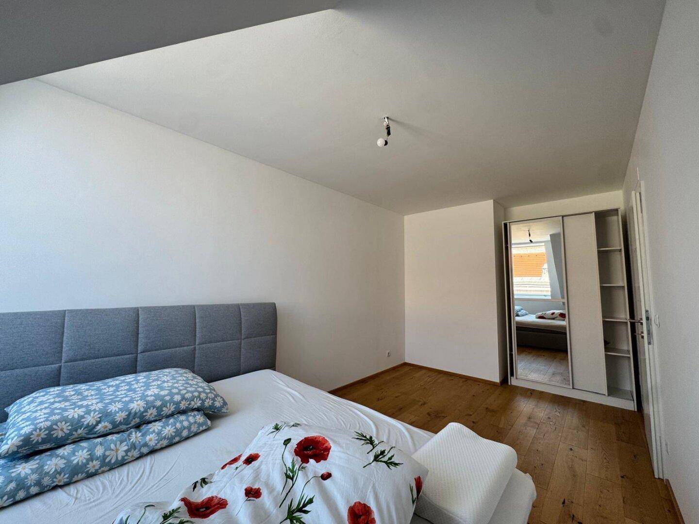 Schlafzimmer mit Holzboden und praktischem Spiegelschrank, bietet ausreichend Stauraum.