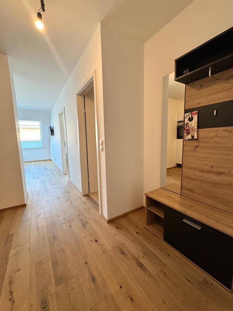 Langer Flur mit Holzboden und moderner Garderobe, verbindet die verschiedenen Wohnbereiche.