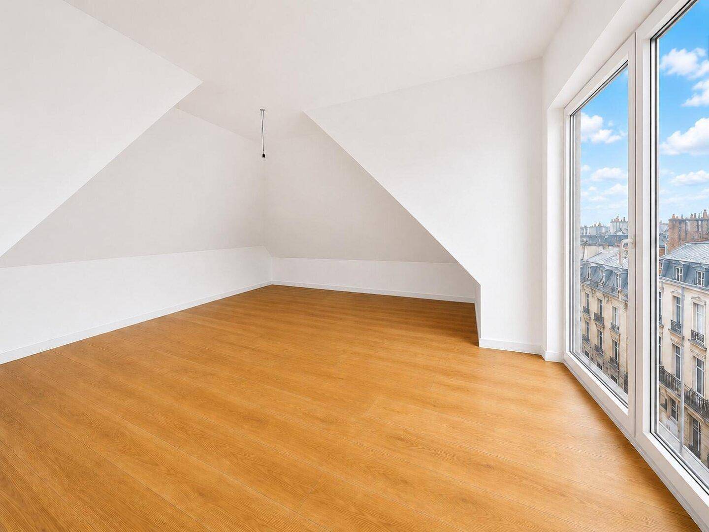 Geräumiger, unmöblierter Raum mit Holzboden und großen Fenstern, ideal für ein Loft-Gefühl.