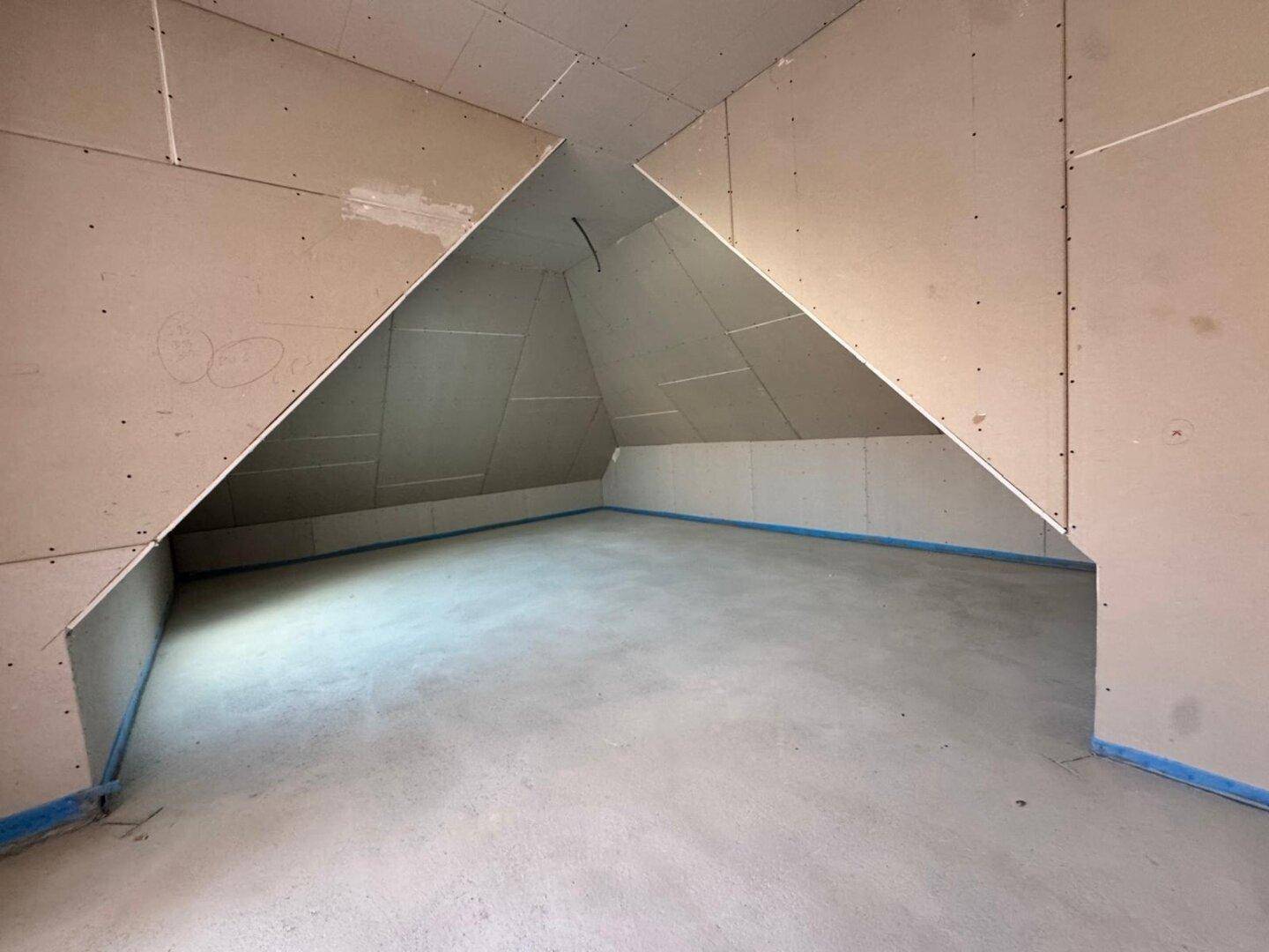 Rohbau-Raum mit ausgeprägten Dachschrägen und Betonboden, bietet viel Gestaltungspotenzial.