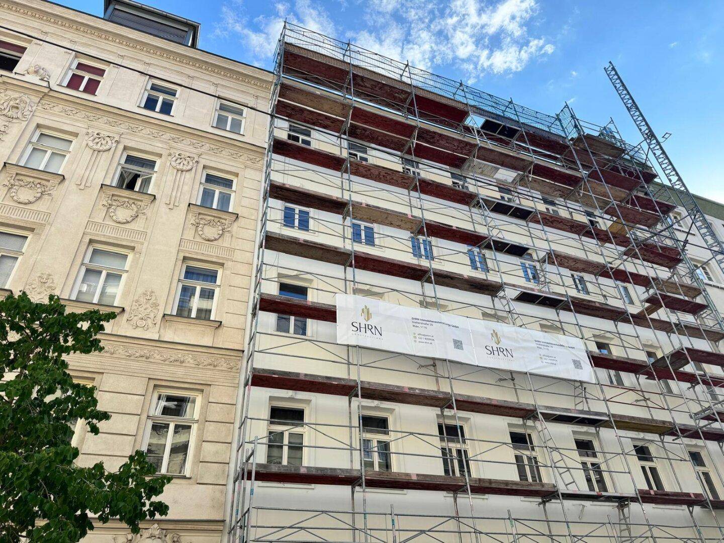 Fassade eines Gebäudes mit Gerüst, das auf Renovierungsarbeiten oder Neubau hinweist.