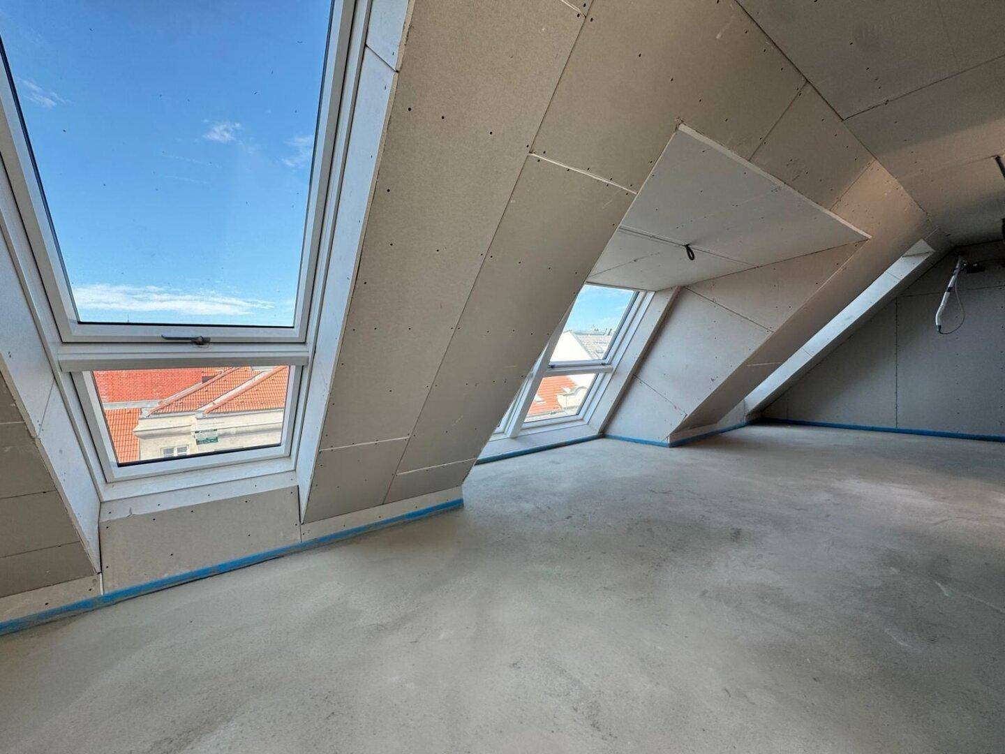 Rohbau eines Raumes mit Trockenbauwänden und Betonboden, der auf den Innenausbau wartet.