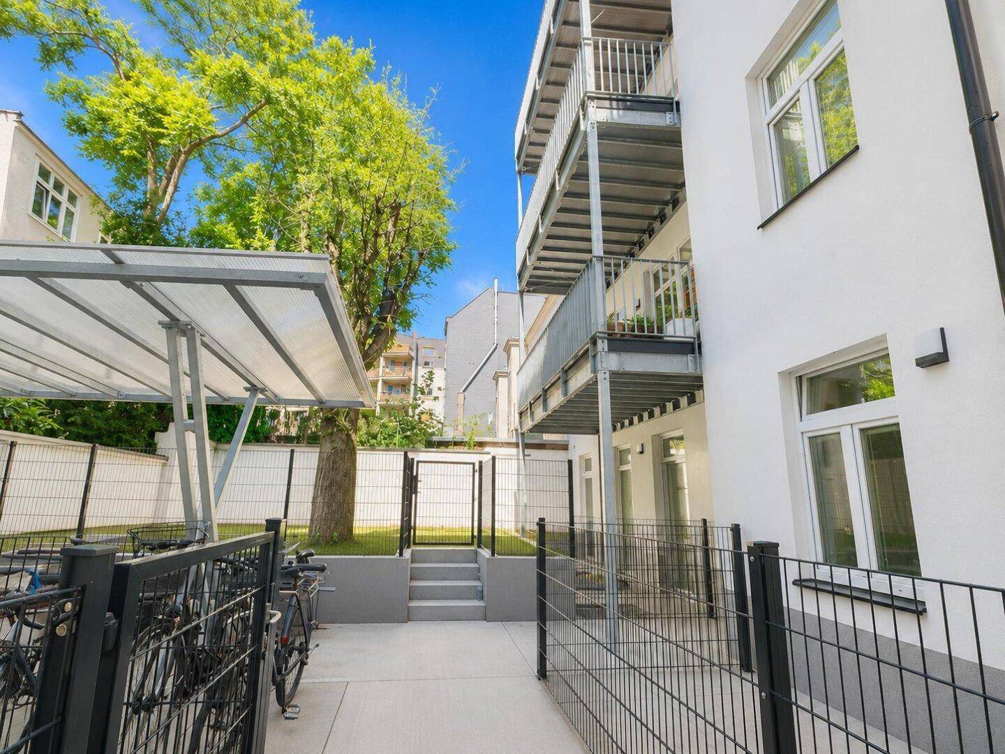 Hinterhofbereich mit Fahrradabstellplätzen, Balkonen und viel Grün.