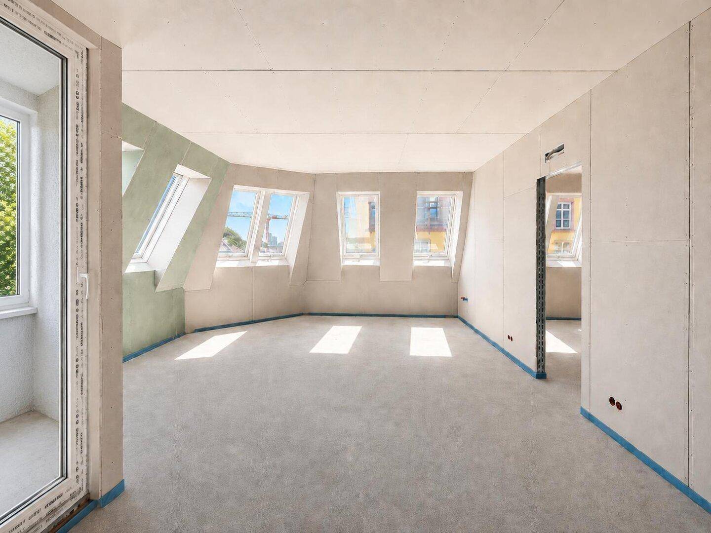 Heller, unfertiger Raum mit Balkonzugang und vielen Dachfenstern, ideal für ein Wohnzimmer.