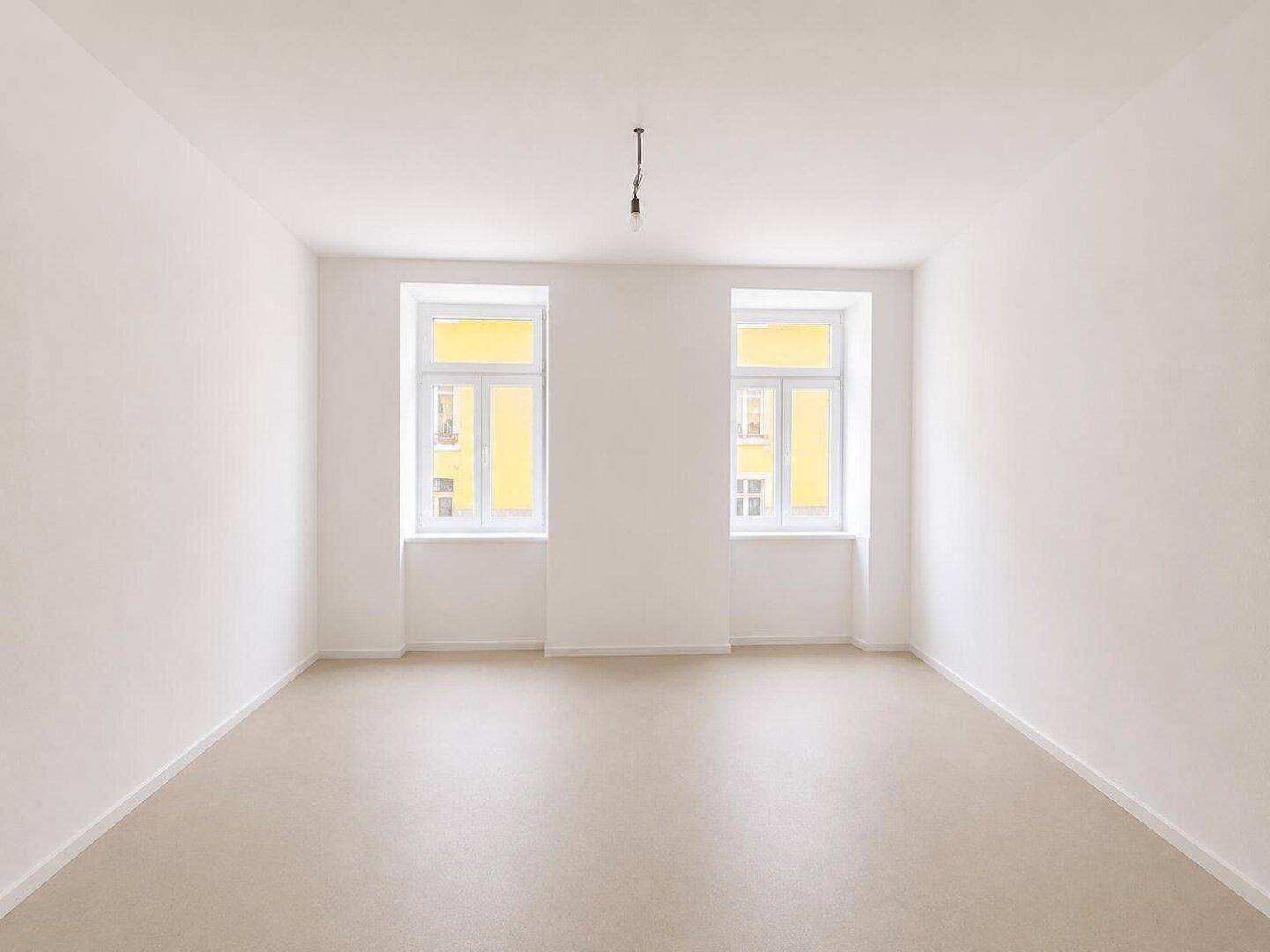 Geräumiges, leeres Zimmer mit zwei großen Fenstern und weiß gestrichenen Wänden, ideal für neue Einrichtung.