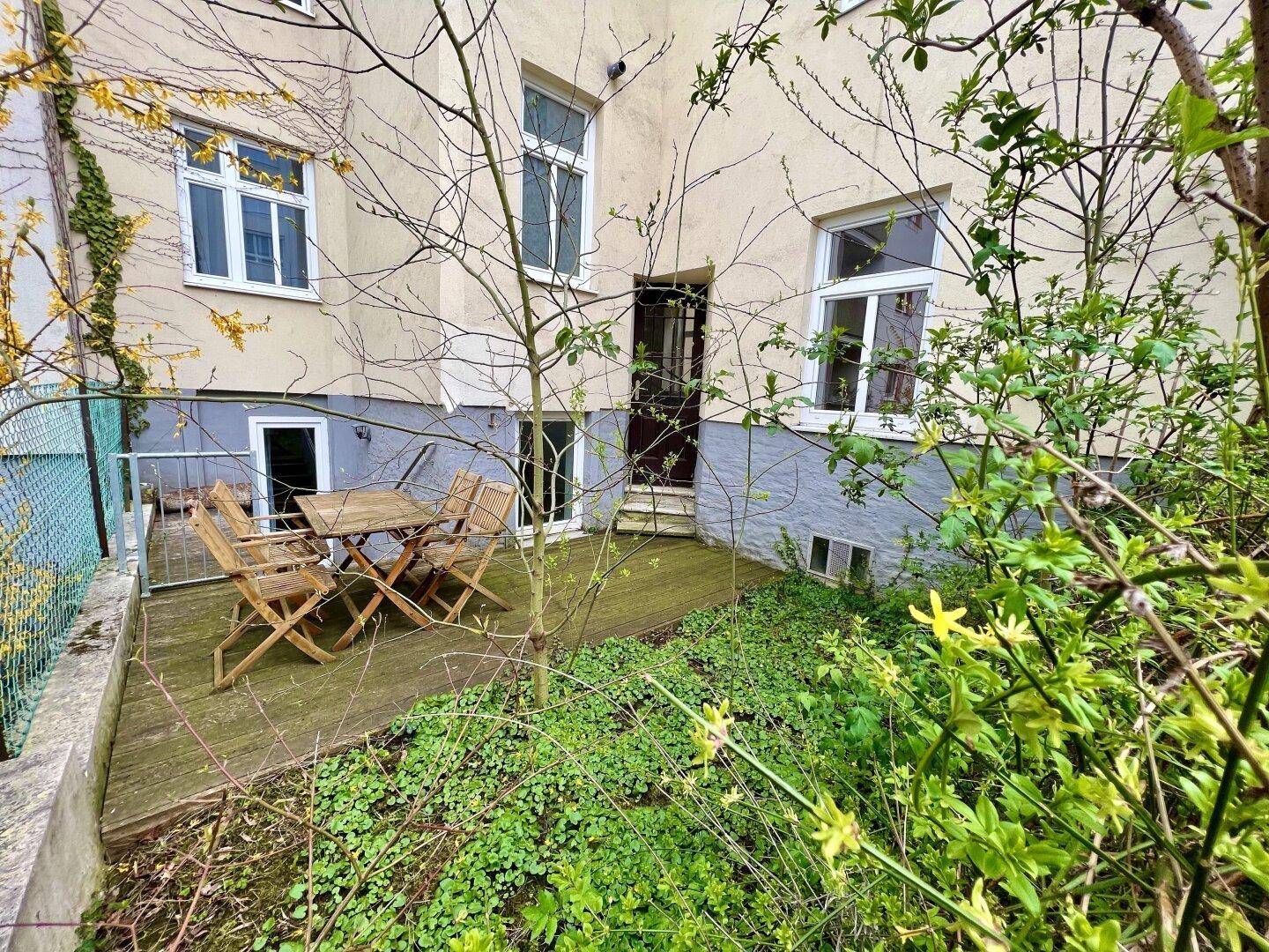 Kleine Terrasse mit Holzboden und Gartenmöbeln im Erdgeschoss des Gebäudes.