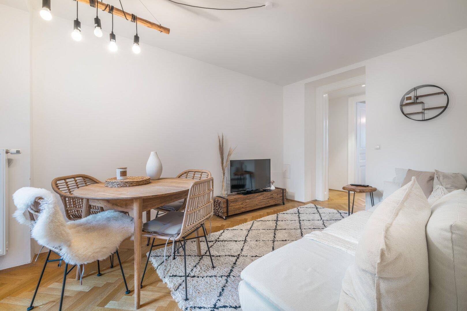 Offener Wohn-Essbereich mit modernem Esstisch, bequemer Couch und Holzboden.