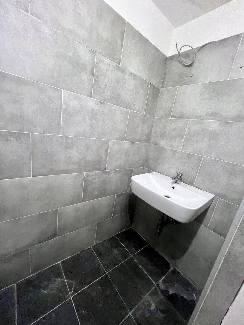 Kleines Gäste-WC mit modernem Waschbecken und grauen Wand- und Bodenfliesen.