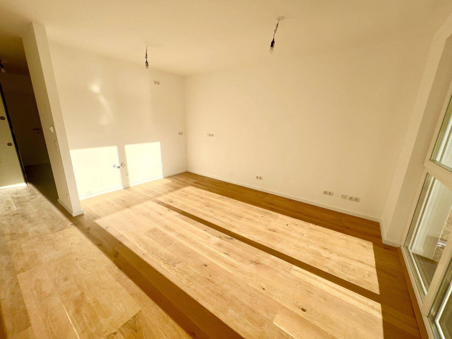 Lichtdurchfluteter Raum mit hellem Holzboden und weißen Wänden, ideal für individuelle Gestaltung.
